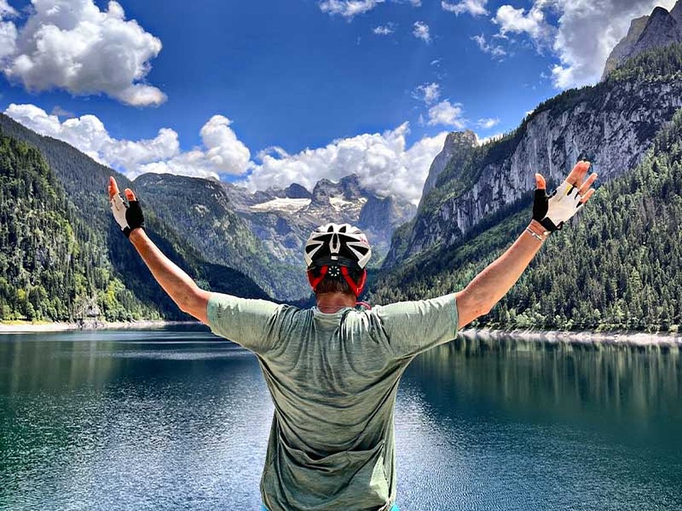 Michaela Dorfmeister von Hinten mit einer die Landschaft umarmenden Geste, im Hintergrund der Gosausee und der Dachstein